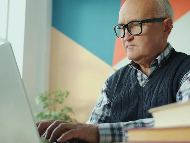 Man wearing glasses working on a laptop